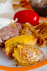 Fried meat with potatoes, stewed cabbage and salted tomatoes, cooked at home. Homemade lifestyle dinner. Close-up, vertical photo.