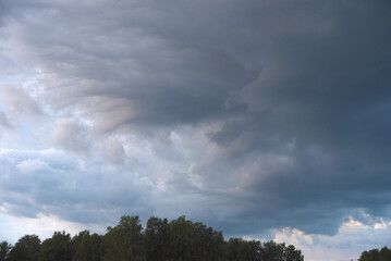 Cumulus rain clouds in the evening sky. Thunderclouds over the forest.