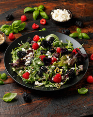Summer berries salad with edible flowers, feta cheese and seeds