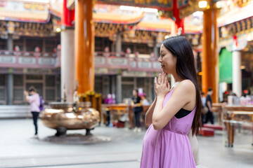 Asian pregnant woman pray at chinese temple