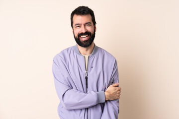 Caucasian man with beard wearing a jacket over isolated background laughing