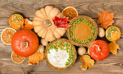 pumpkins, pumpkin pies, nuts, autumn leaves and dried oranges on a wooden table. Thanksgiving table