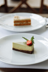 delicious cake with green cream, topped with fresh, fragrant strawberries and layered with black cake, is served on a beautiful white plate in a cozy, charming café