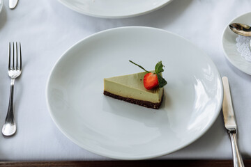 delicious cake with green cream, topped with fresh, fragrant strawberries and layered with black cake, is served on a beautiful white plate in a cozy, charming café