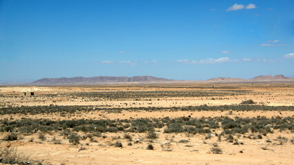 Naklejka premium Arid landscape with mountains in the distance on the road to Douz, Tunisia