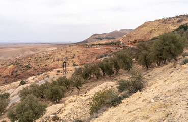 Arid Moroccan landscape near Marrakech, sparse vegetation, rolling hills, dry terrain, distant mountains