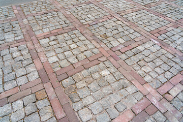 Cobblestone pavement with red brick pattern, geometric design, weathered stones, rustic outdoor setting