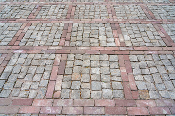 Fototapeta premium Cobblestone pavement with red brick pattern, geometric design, weathered stones, rustic outdoor setting