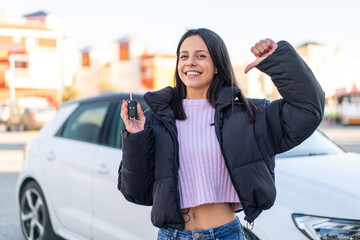 Young woman at outdoors holding car keys at outdoors proud and self-satisfied