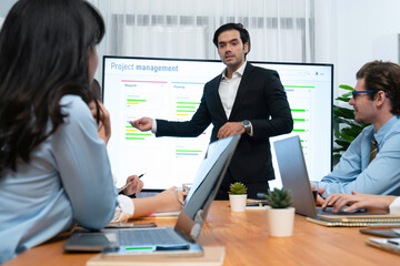 Project manager planning schedules for business task at meeting room, Gantt chart software show on TV screen. Multi ethnic diversity business people and modern business project management. Habiliment