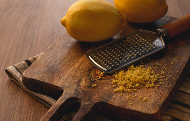 lemons and grated orange peel, with a zest grater, on a chopping board, close-up, no people,