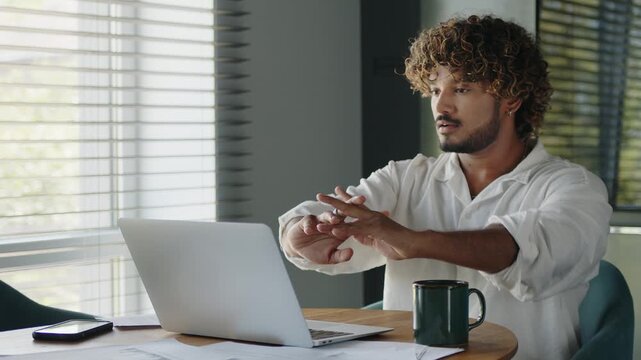 Indian bearded businessman freelancer at home office workplace starts working on laptop. The beginning of the working day.