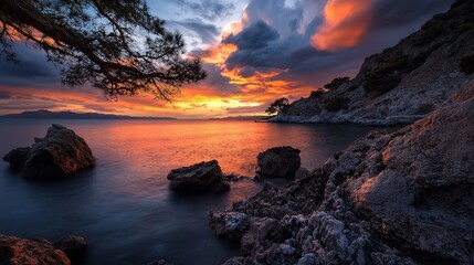  A sunset over a body of water Rocks in the foreground Tree on the opposite shore