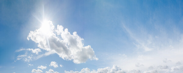cloudscape: sun rays shining through clouds blocking the sun in blue sky