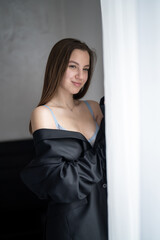 Beautiful Young Girl Wearing Blue Bra and Black Suit Jacket is Looking Out of The Window. Bedroom Interior