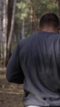Muscular runner running on road through forest. Back view. Athletic man running on road through forest. Athletic man running on trail through autumn forest