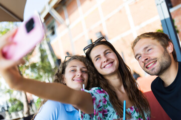 Group of friends taking a selfie outdoors in a bright sunny day