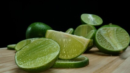 Close-up, a vibrant slice of fresh lime rests upon a rustic wooden cutting board, exuding freshness and vitality. The translucent membranes of the green lime slice placed on cutting board. Comestible.