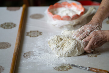 Close up of an old woman hands kneading bread dough on a table