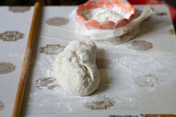 Bread dough on a table with rolling pin and flour next to it