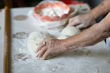 Close up of an old woman hands kneading bread dough on a table