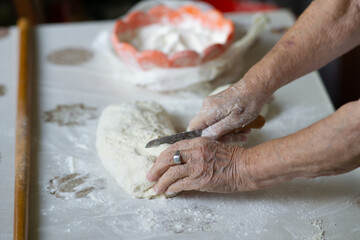 Close up of an old woman hands kneading bread dough on a table