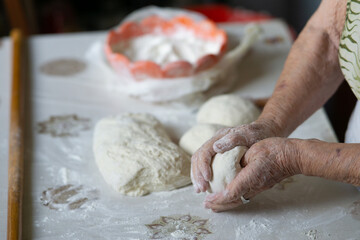 Close up of an old woman hands kneading bread dough on a table