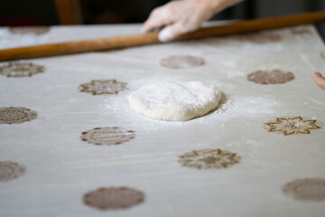 close up of grandmother's old wrinkled hands rolling dough with a rolling pin. Elderly woman rolling out dough with a rolling pin