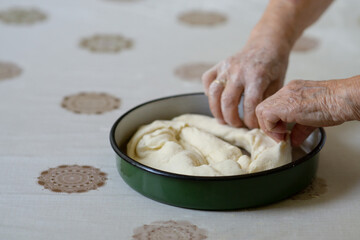 Old woman hands putting stuffed dough in a pan