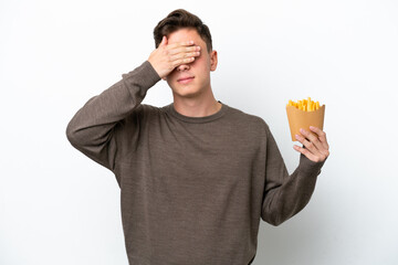 Young Brazilian man holding fried chips isolated on white background covering eyes by hands. Do not...