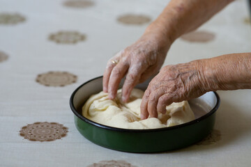 Old woman hands putting stuffed dough in a pan