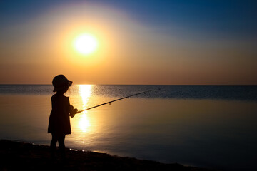 Fototapeta premium A Happy child fisherman fishing by the sea on nature silhouette travel