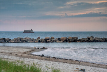 Twilight scene on Cape Cod. Soft pastel colored sky over Cape Cod Bay with passenger tour boat traveling along coastline near Corporation Beach in East Dennis, Massachusetts.