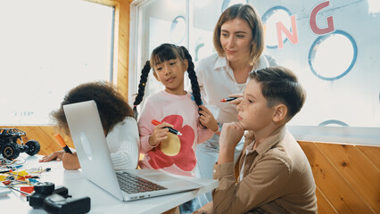 Smart teacher teaching and looking student using laptop at classroom. Professional instructor...