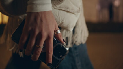 Woman hand holding smartphone at night city stroll closeup. Unknown woman phone