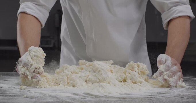 Chef prepares pasta dough. Male hands knead dough with hands. Traditional Italian pasta recipe. Dough preparation