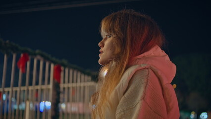 Stylish woman standing night street looking on amusement park lights closeup. 