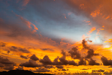 Fototapeta premium A breathtaking aerial view capturing a vibrant sunset over the Phuket countryside. The sky is ablaze with rich hues of yellow, orange, pink, and purple, while dramatic clouds float above the city