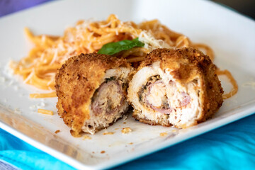 Traditional chicken Kiev, breaded, stuffed and fried served with spaghetti with tomato sauce and grated parmesan cheese