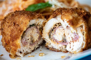Traditional chicken Kiev, breaded, stuffed and fried served with spaghetti with tomato sauce and grated parmesan cheese