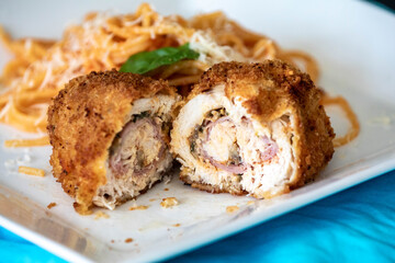 Traditional chicken Kiev, breaded, stuffed and fried served with spaghetti with tomato sauce and grated parmesan cheese