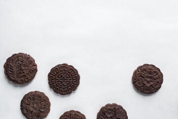 Overhead view of stamped chocolate cookies on a parchment lined baking tray, top view of embossed chocolate sugar cookies on a white background