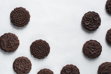 Overhead view of stamped chocolate cookies on a parchment lined baking tray, top view of embossed chocolate sugar cookies on a white background