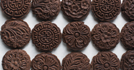 Overhead view of stamped chocolate cookies on a parchment lined baking tray, top view of embossed chocolate sugar cookies on a white background