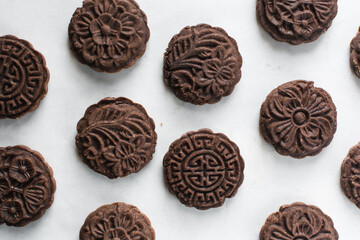 Overhead view of stamped chocolate cookies on a parchment lined baking tray, top view of embossed chocolate sugar cookies on a white background