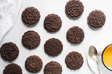 Overhead view of stamped chocolate cookies on a parchment lined baking tray, top view of embossed chocolate sugar cookies on a white background