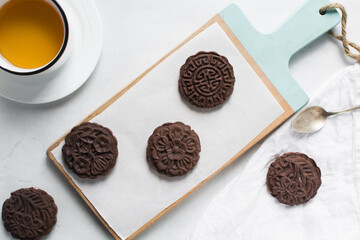 Overhead view of stamped chocolate cookies on a parchment lined baking tray, top view of embossed chocolate sugar cookies on a white background
