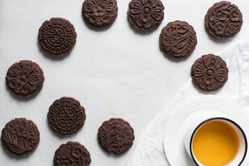 Overhead view of stamped chocolate cookies on a parchment lined baking tray, top view of embossed chocolate sugar cookies on a white background
