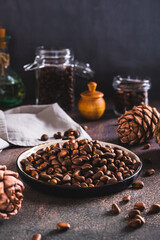 Ripe pine nuts in the shells on a plate and boiled pine cones on the table vertical view