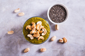 Fototapeta premium Close up of organic chia pudding with pistachio butter and cashews in a glass on top view